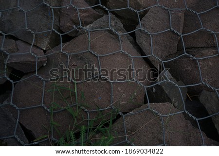 The background of old rusty steel wire mesh stuck to the rock.