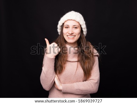 Pretty young woman showing thumb up is smiling at the camera.