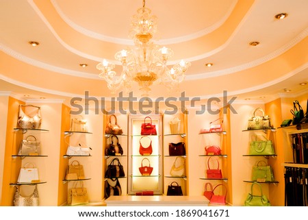 Selection of designer handbags on-shelf display in glamorous boutique. Royalty-Free Stock Photo #1869041671