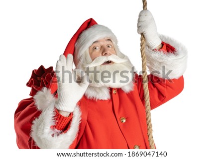 Funny Santa grandfather shows signs of acceptance while going down the rope. White background.
