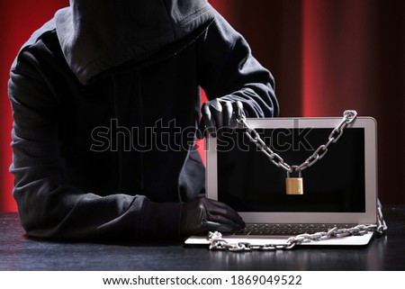 International hacker in black pullover and black mask trying to hack government on a black and red background. Cyber crime . Cyber security. 