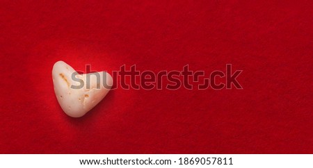 heart shaped stone on red felt background. Copy space. Love concept.