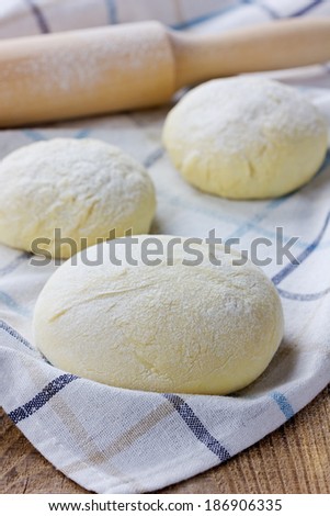 Dough with rolling pin on a linen napkin on the wooden table