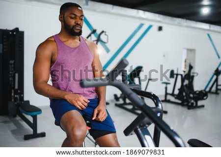african man using stationary bicycle in a gym.