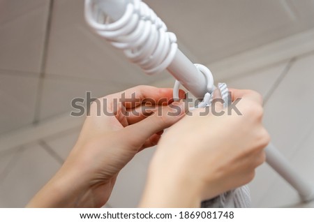 Close - up of women's hands hanging a gray curtain in the bathroom Royalty-Free Stock Photo #1869081748
