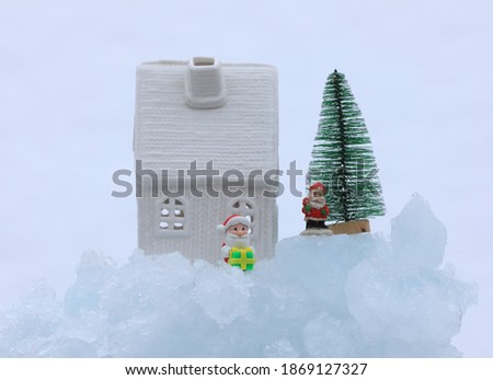 white toy christmas house and toy santa claus on ice