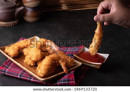 The hand was holding the fried shrimp.
