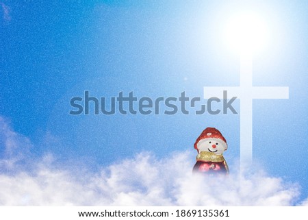 Christian cross and snow man doll on the clouds and blue sky with shining light and snow. 