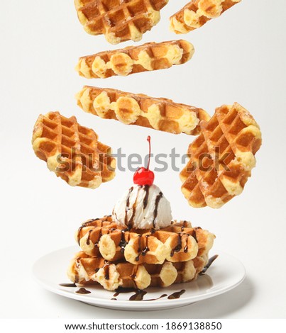 Belgian Liege Waffles With Ice Cream Ball And Chocolate Sauce, Cherry On Top And Levitation Waffles Around Plate Isolated On White Background. Side View. Royalty-Free Stock Photo #1869138850
