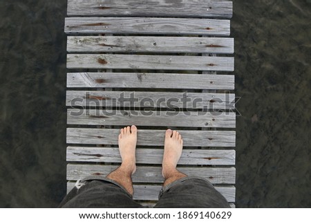 A top view of a man's feet on a wooden jetty. 