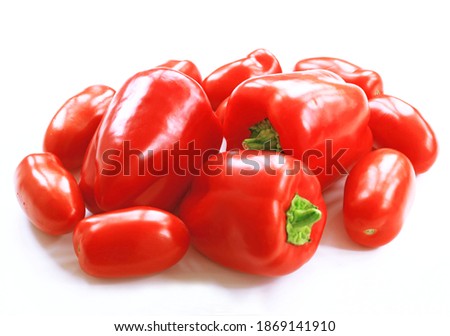 Three red peppers and plum tomatoes on a white background