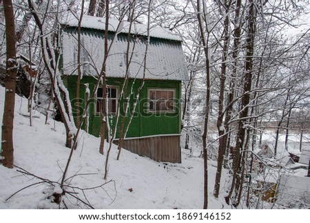 Scene of a winter forest and an authentic village with old wooden houses covered with snow. The main subject is deliberately shifted to the side to enhance the expressiveness of the image