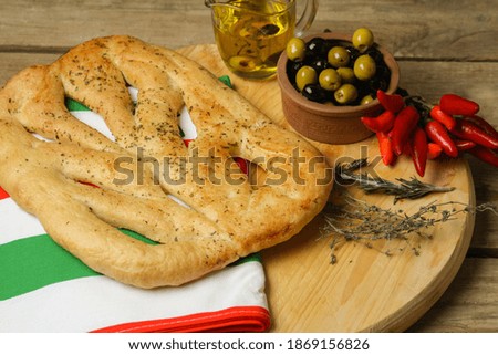 Italian Food Flat Bread Focaccia With Green And Black Olives, Oil, Chilli Peppers On Wooden Table. Top View.