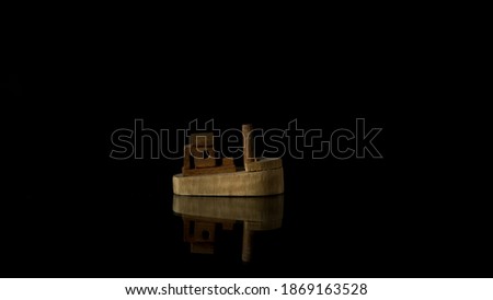 Wooden boat with reflection on black background