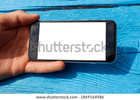 phone mock up in hand in horizontal position on the background of the boards. phone in hand on an old blue table