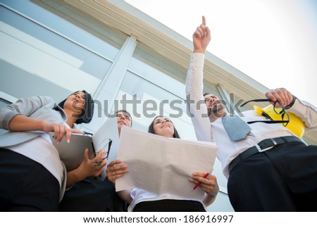 Engineers at construction site pointing finger to a building