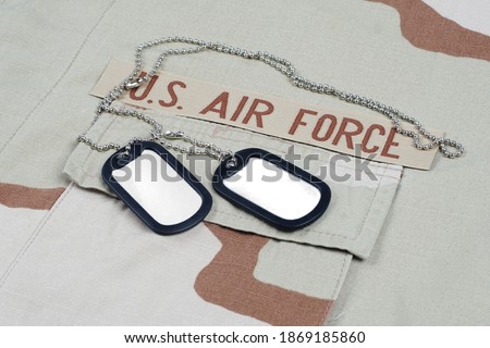 US AIR FORCE branch tape with dog tags on desert camouflage uniform background