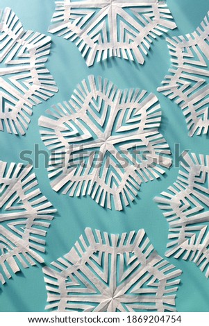 Paper cut snowflakes as a pattern on a light blue background. Christmas card. Light and shadow.