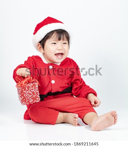 Baby wearing christmas santa costume holding gift box isolated on white background