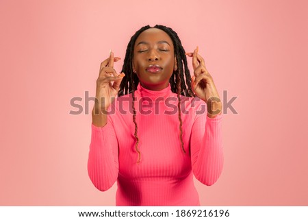 Hopefulness. Young african-american woman in pink outfit posing isolated on pink background. Copy space for ad. Half-length studio shot. Concept of human emotions, facial expression.