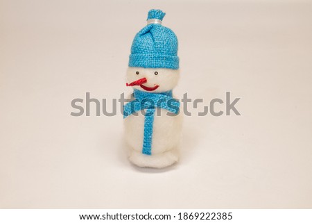 christmas toy snowman with a red nose in a blue hat with a scarf on a white background