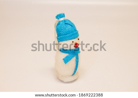christmas toy snowman with a red nose in a blue hat with a scarf on a white background