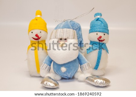 three christmas toys two snowmen with red noses and santa claus in yellow and blue hats and scarves isolated on white background