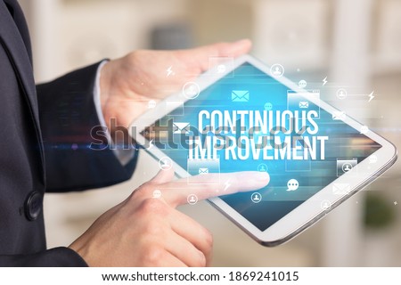 Close-up of a tablet searching CONTINUOUS IMPROVEMENT inscription, modern technology concept