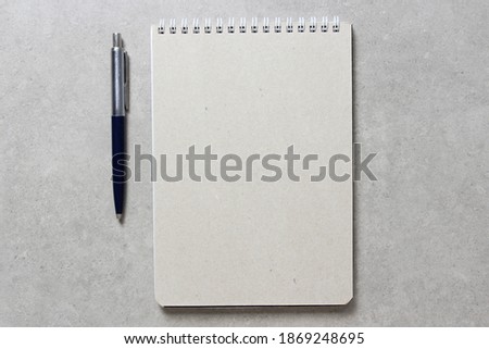 A spring notebook with a sheet of craft paper A5 with a ballpoint pen on light grey concrete background. Concept of new idea, business plan and strategy, development and implementation of content