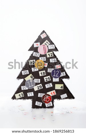 Artificial fir Christmas tree decorated with numbers isolated on a white background, numbers of a paper around the decoration, fir tree made of wood and metal in brown color, winter holiday symbol