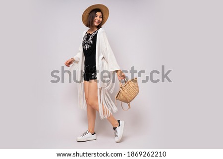 Full lenght studio photo of glad woman with short hairstyle in stylish boho summer outfit. straw hat and bag. 