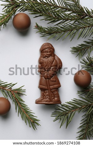 Flat lay composition with chocolate Santa Claus, fir tree twigs and sweets on white background
