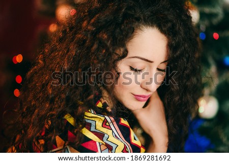 A closeup of caucasian nice girl with closed eyes in front of christmas tree