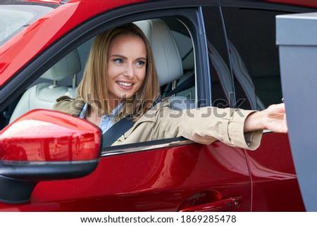 Woman getting ticket from parking meter in underground parking Royalty-Free Stock Photo #1869285478