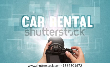Close-up of a hand holding digital camera with CAR RENTAL inscription, traveling concept
