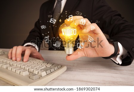 Businessman holding light bulb with VIDEO inscription, social media concept