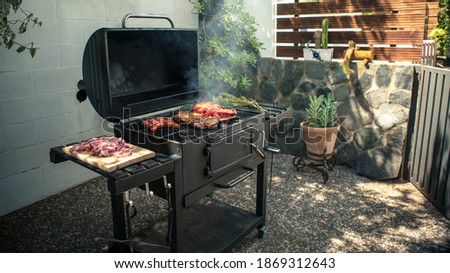 Chef cooking a delicious pork ribs with red peppers on the BBQ grill. Cook pork meat on grilled meat. Food cooked with grilling barbecue in backyard of house Royalty-Free Stock Photo #1869312643