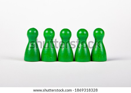 five green wooden figurines in a row on white background, grouped