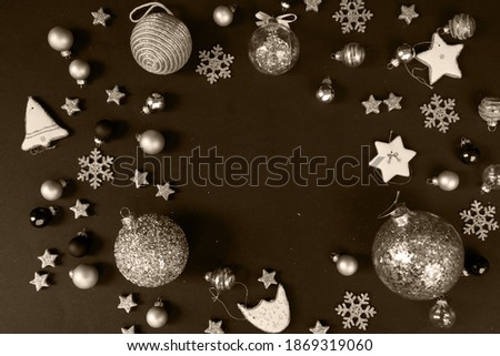 Golden christmas decorations with gingerbread cookies over black background, frame with copy space, toned