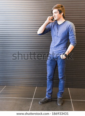 Young man talking on the phone indoor against black background
