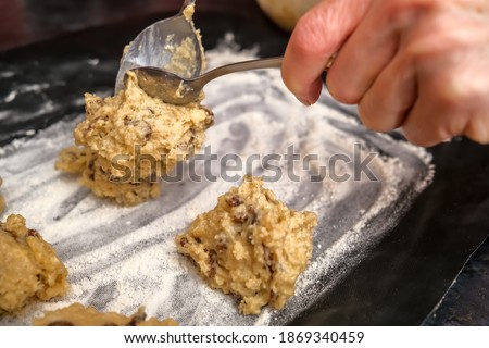 Norwich, Norfolk, UK – December 06 2020. Illustrative editorial photography of an unidentifiable home baker spooning cake mixture on to a lined and floured baking tray