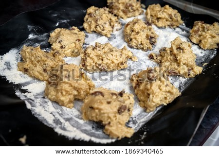 Norwich, Norfolk, UK – December 06 2020. Illustrative editorial photography of a tray of homemade cake mixture moulded in to individual mounds on a floured baking tray ready to be cooked in the oven