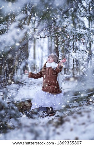 Blurred toddler girl enjoying winter in the snow forest, vertical                   