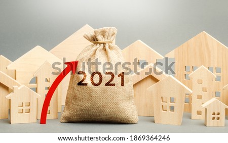 2021 money bag with up arrow and miniature houses. Real estate planning and financing concept. Housing market. Mortgage, loan, investment. Repairs and refinance home. Investing in construction Royalty-Free Stock Photo #1869364246