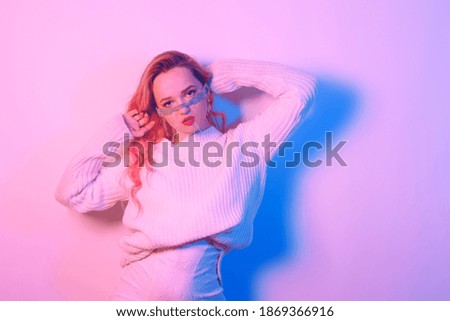 Girl in a white sweater in neon light. Masked woman, fashion photo.