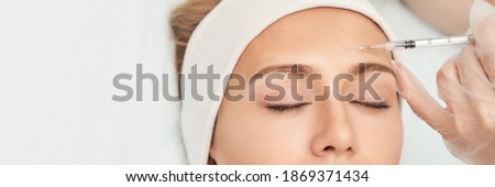Forehead injection at spa salon. Doctor hands. Closeup. High quality. Pretty female patient. Beauty treatment. Healthy skin procedure. Young woman face. Light background. Plasmolifting rejuvenation Royalty-Free Stock Photo #1869371434