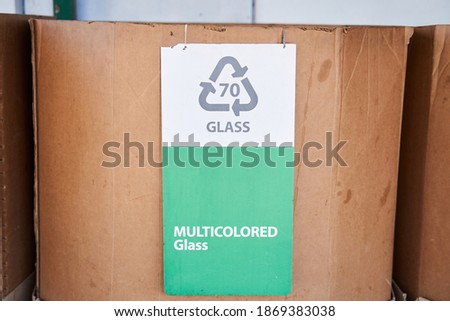 Portrait view of the cardboard box with recycling symbol for the multicolored glass standing at the at the waste sorting plant. Stock photo