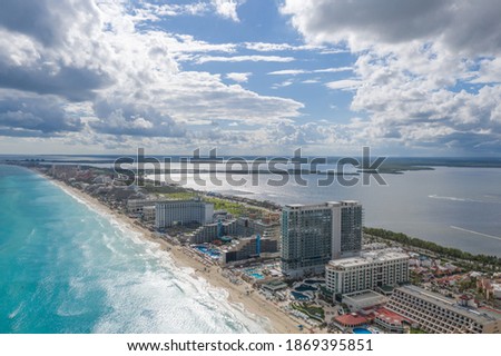 Aerial panoramic view of Cancún in Quintana Roo, México with a cloudy sky and the blue turquoise caribbean ocean as background.