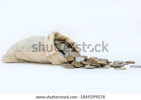 a bag of money lies and coins poured out of it. controlling the level of costs. Profit and liquidity. Cash management. Giving out money. White background, big plan, selective focus, minimalism. Royalty-Free Stock Photo #1869399076