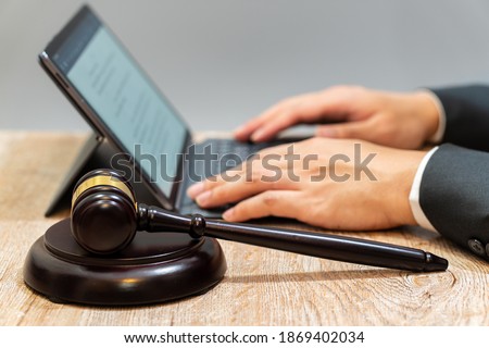 Digital transformation in legal profession: Wooden gavel was placed as the subject, judge or lawyer typing tablet' s keyboard as background.
